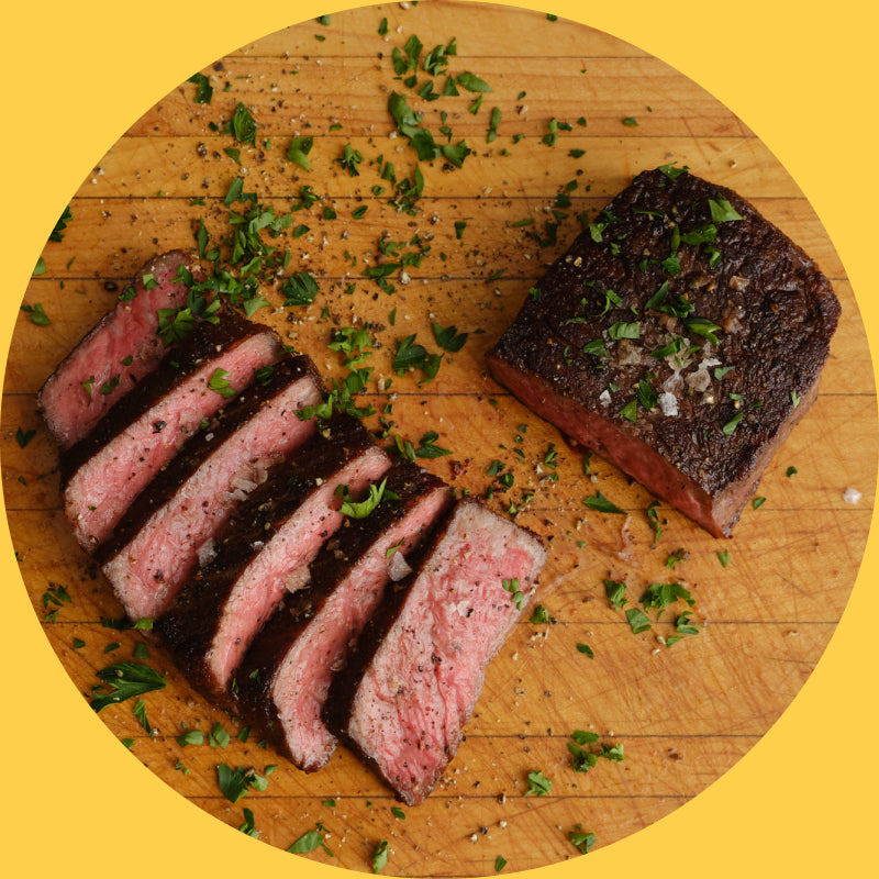 A perfectly cooked steak, sliced neatly and sprinkled with herbs.